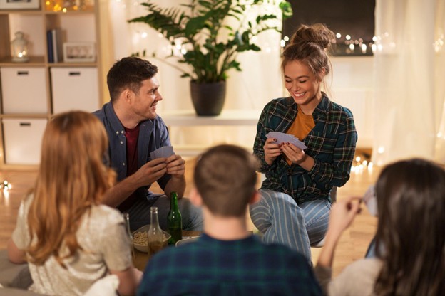 Friends and Family Sitting Around Laughing Playing Cards