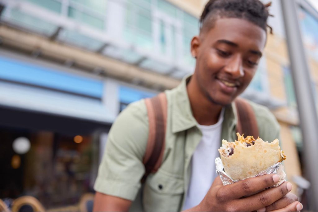 A Guy Eating a Burrito from a Restaurant at Logan Circle
